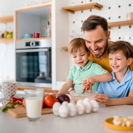 Smiling father with kids preparing healthy food and spending time together