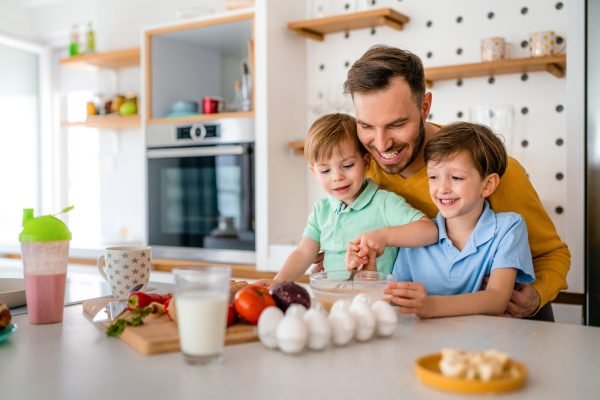 Smiling father with kids preparing healthy food and spending time together